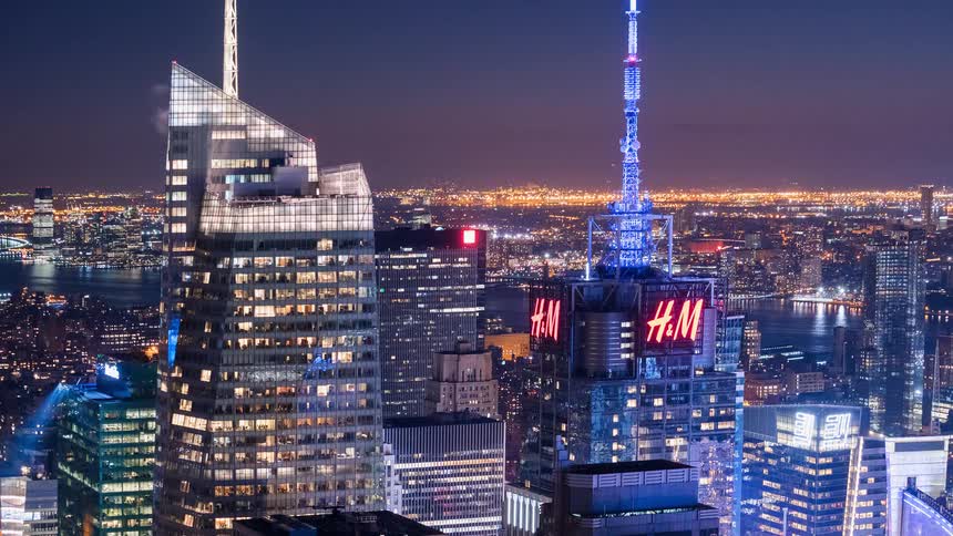 A dazzling nighttime view of the New York City skyline with the iconic Times Square towers glowing and changing colors