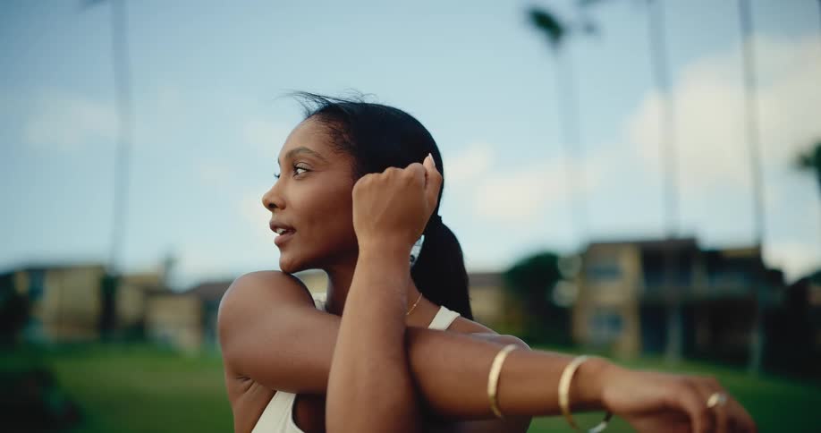 Slow motion close-up of a beautiful athletic woman stretching her arms while warming up in a park