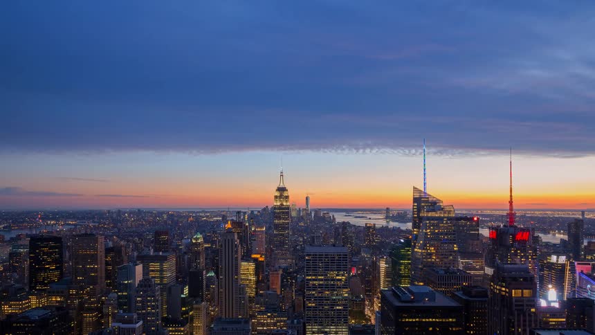 A stunning day-to-night time-lapse of the iconic New York City skyline as a vibrant sunset transitions to a glittering urban nightscape