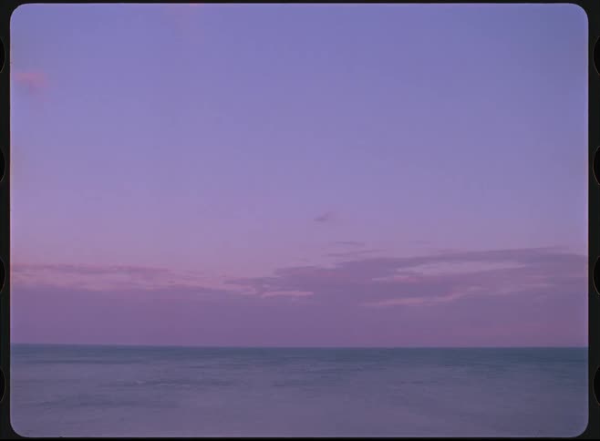A tranquil and dreamy view of the ocean meeting a pastel purple sky at twilight with a vintage film look