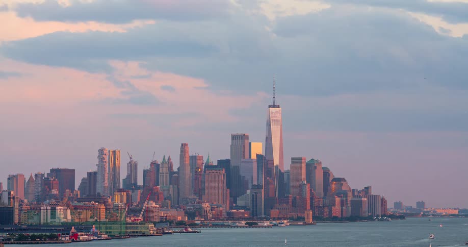 The iconic New York City skyline, featuring One World Trade Center, is bathed in the warm light of a beautiful sunset in this stunning timelapse