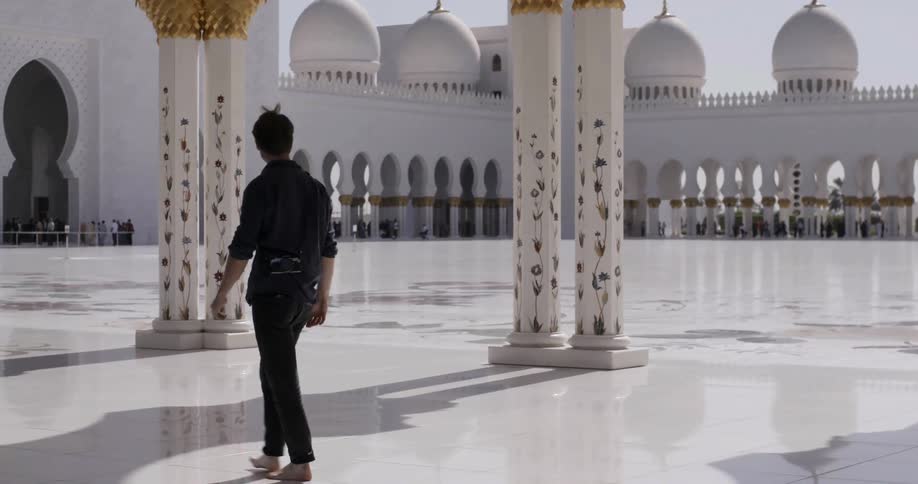 Man walks barefoot over tiled ground on a sunny day