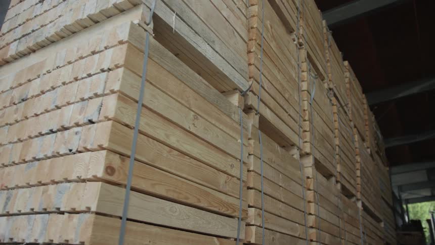Low angle view of massive stacks of bundled timber planks stored inside a large industrial warehouse
