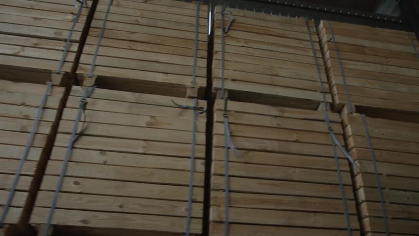 Wooden shipping crates and pallets are stacked high inside a large storage warehouse
