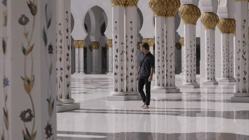 A man walks among ornate building pillars
