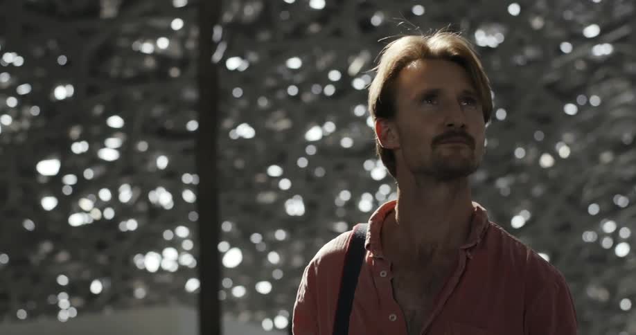 Man carrying a camera looks around at a structure