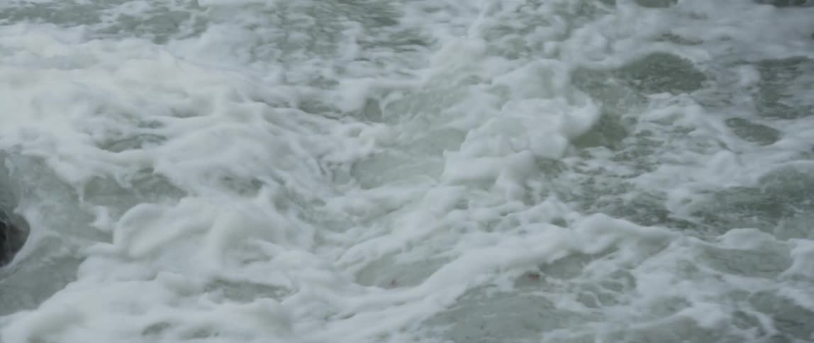 A powerful river churns and flows in a turbulent display of whitewater rapids seen in a slow-motion close-up