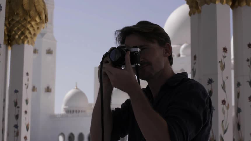 A man takes a photograph on a sunny day