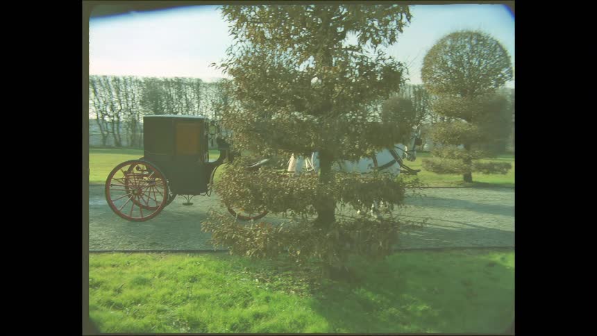Behind-the-scenes of a period drama film set featuring a horse and carriage on the grounds of a large villa, captured in a vintage 8mm style