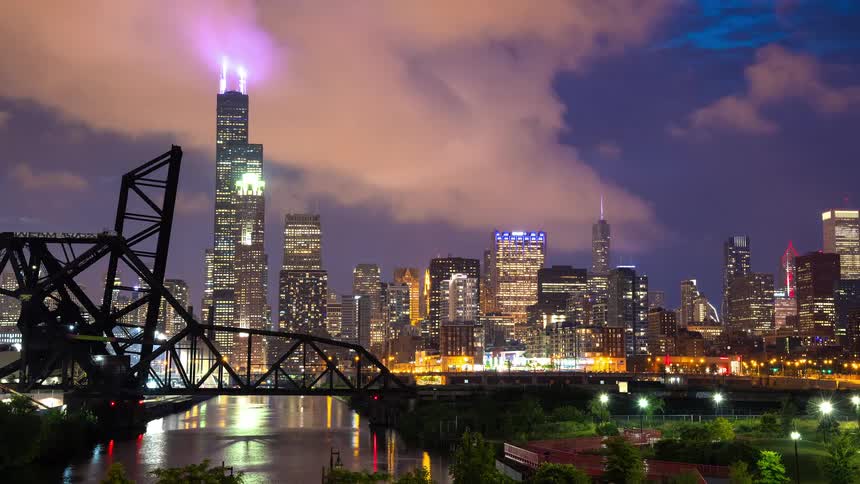 Stunning timelapse of the Chicago skyline at dusk, featuring the Willis Tower, a drawbridge, and boat traffic on the river as clouds float by