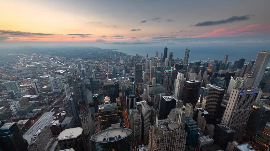 A stunning day-to-night time-lapse from an aerial perspective over the Chicago skyline as city lights illuminate the sprawling metropolis