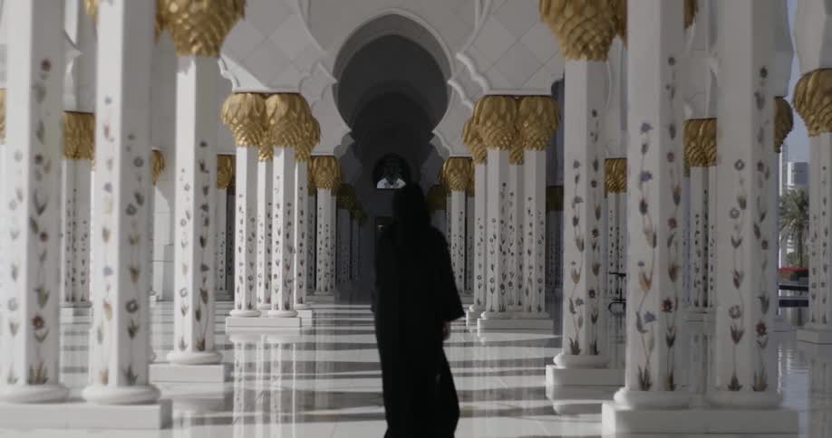 Hooded figure walks through a cathedral