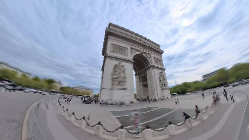 A dynamic fisheye time-lapse orbiting the iconic Arc de Triomphe in Paris as crowds of tourists and traffic move quickly around the monument