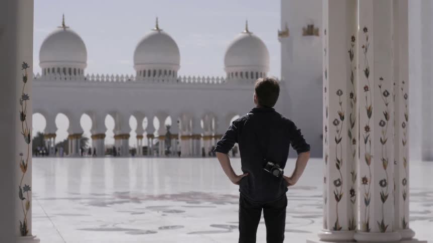 Man stands with hands on his hips looks out at a building