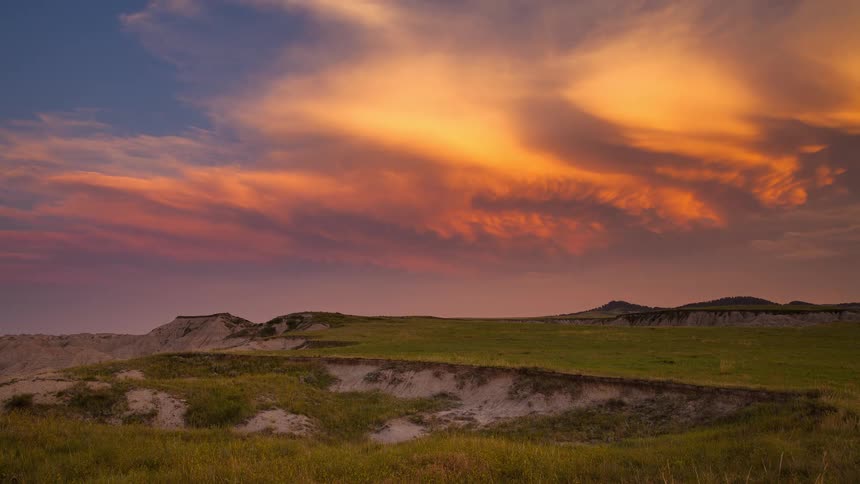 A beautiful time-lapse of a vibrant, fiery sunset over the grassy plains of the Badlands