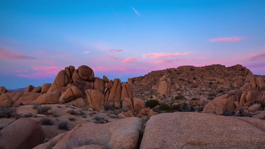 A stunning timelapse captures the vibrant colors of sunset fading to twilight over the unique rock formations of a desert landscape