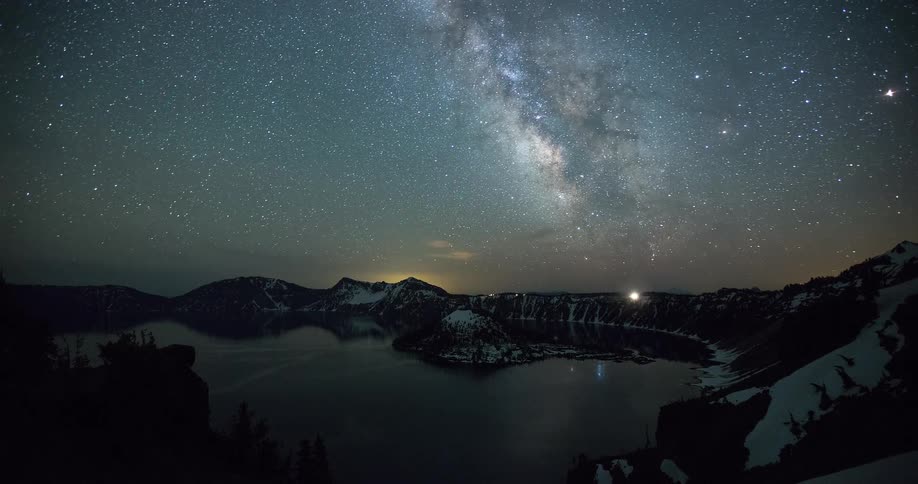An incredible timelapse captures the Milky Way galaxy and countless stars rotating in the night sky above a serene mountain lake