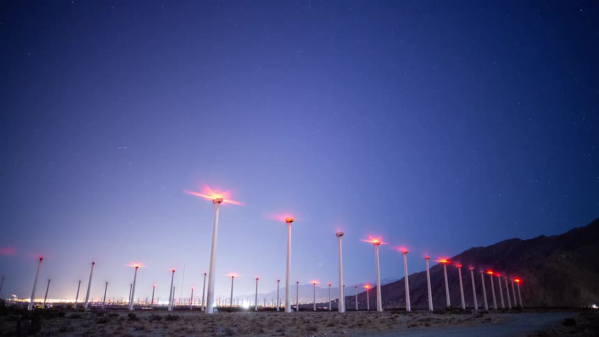 A stunning night time-lapse shows wind turbines spinning under a brilliant starry sky in the California desert