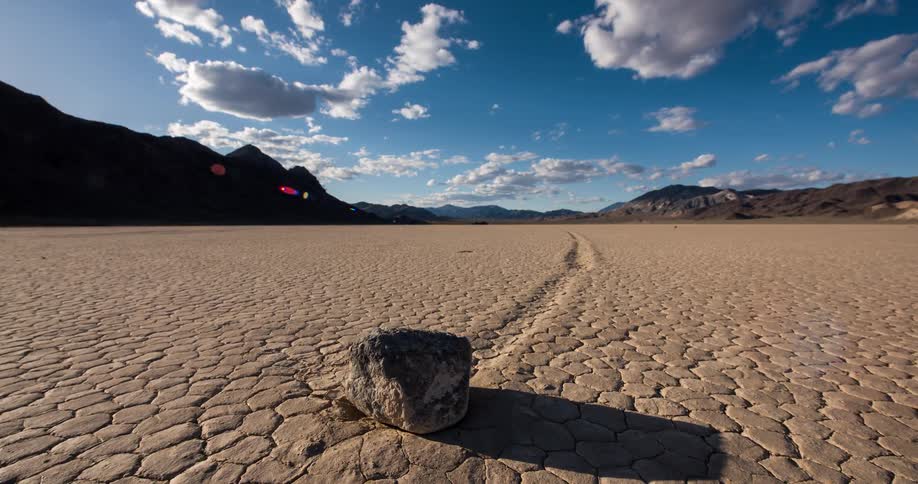 A timelapse of a famous sailing stone on the cracked earth of Racetrack Playa in Death Valley as clouds and shadows move during sunset