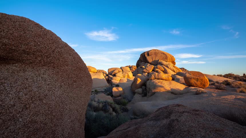 A slow dolly shot reveals stunning desert rock formations as the golden hour light fades in this beautiful sunset timelapse