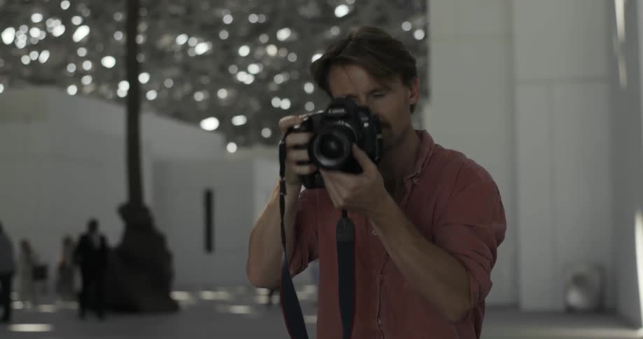 Man looks down at his camera and takes picture of building
