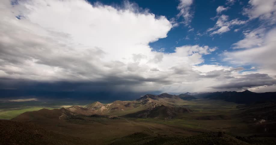 Sunbeams pierce through dramatic storm clouds in a breathtaking timelapse over a green mountain valley