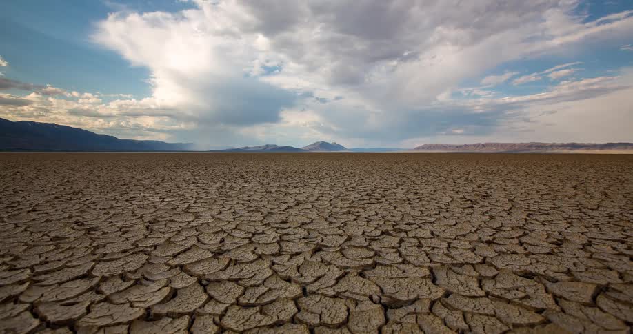 A dramatic timelapse shows clouds moving and shadows shifting across a vast, cracked desert floor