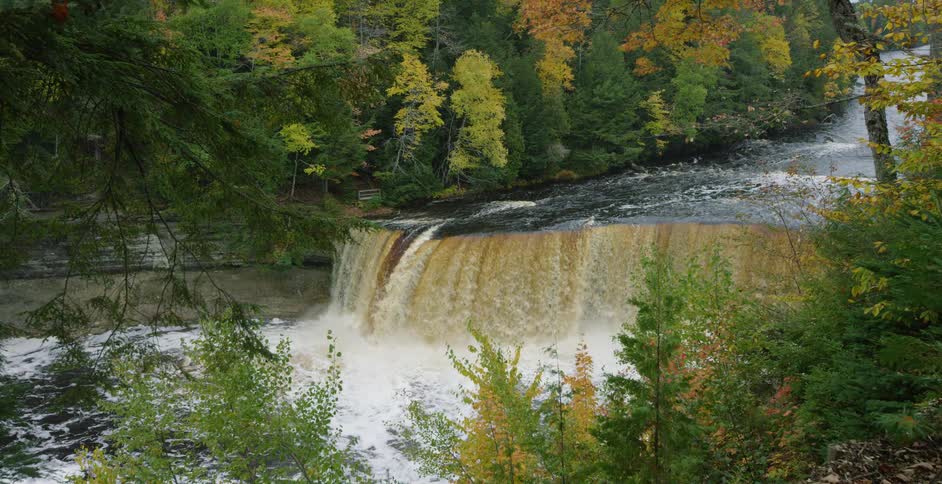 A scenic wide shot of Tahquamenon Falls zooms out to reveal the beautiful autumn foliage in Michigan's Upper Peninsula