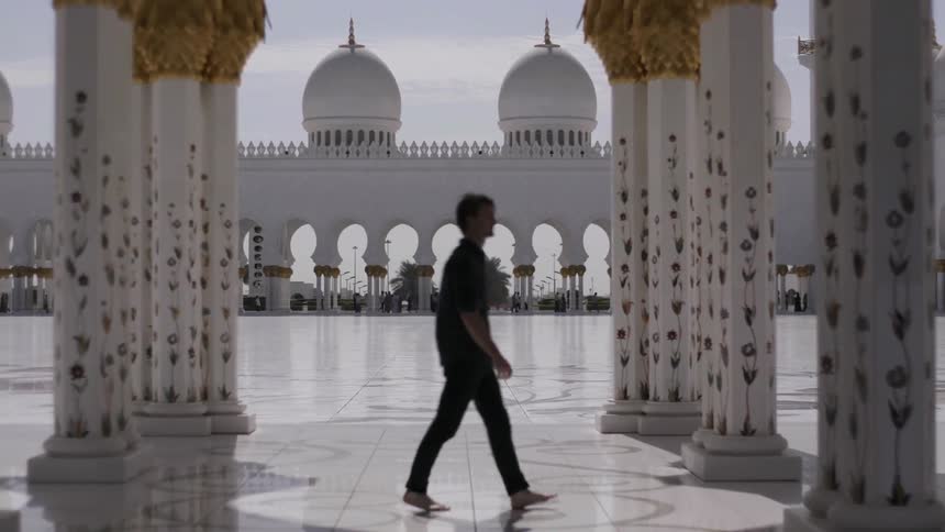 Man walks barefoot over tiled ground on a sunny day