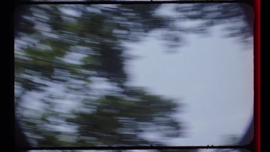 A dizzying point-of-view shot from vintage film shows the sky and trees spinning rapidly before falling to the grass