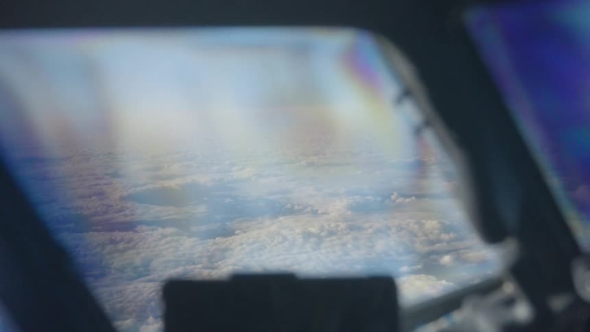 A serene view from an airplane cockpit flying high above a sea of fluffy white clouds