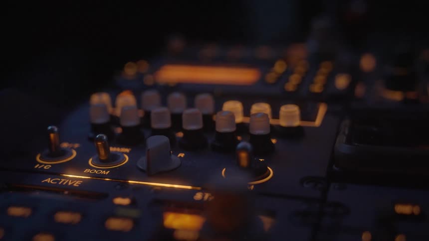 A detailed close-up of a dimly lit airplane cockpit control panel with illuminated switches and dials at night