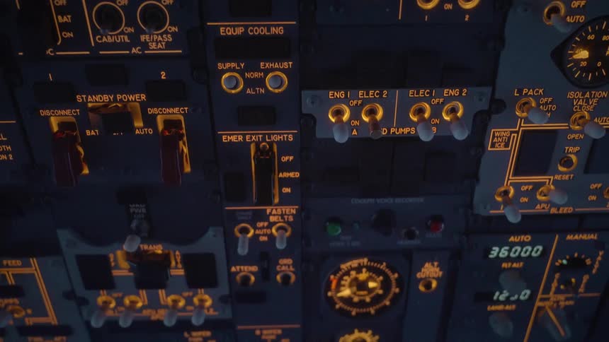 A detailed view of the illuminated overhead instrument panel inside an airplane cockpit at night