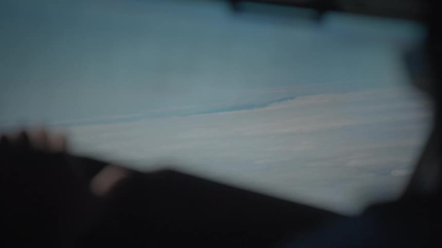 A serene, out-of-focus view from an airplane window flying over a vast sea of white clouds
