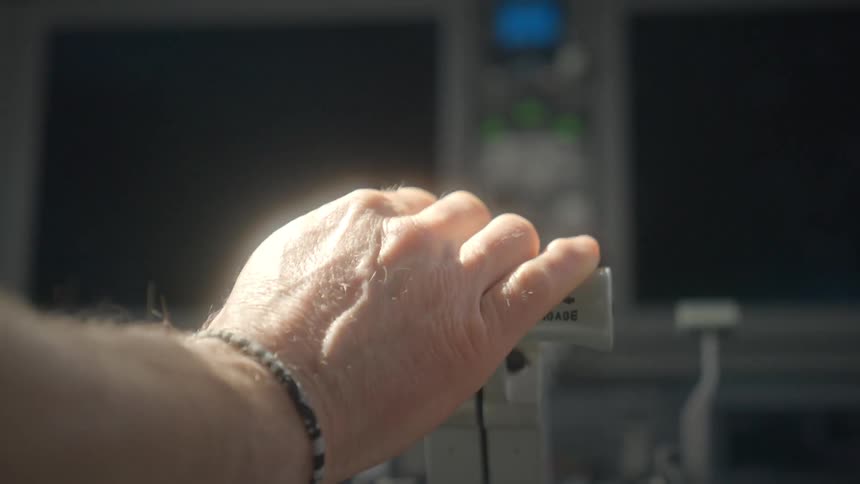 Close-up of a pilot's hand resting on the throttle controls in an airplane cockpit during a flight