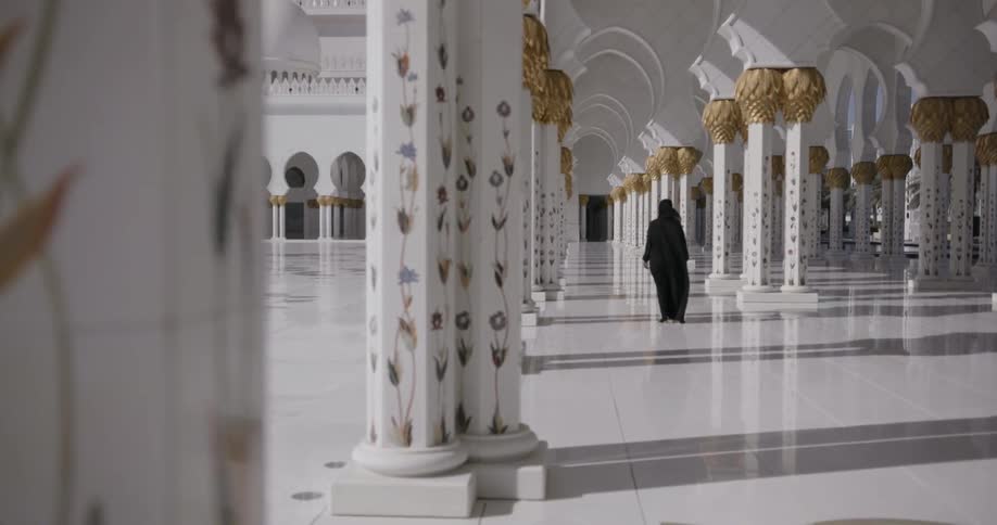 Hooded figure walks through a cathedral