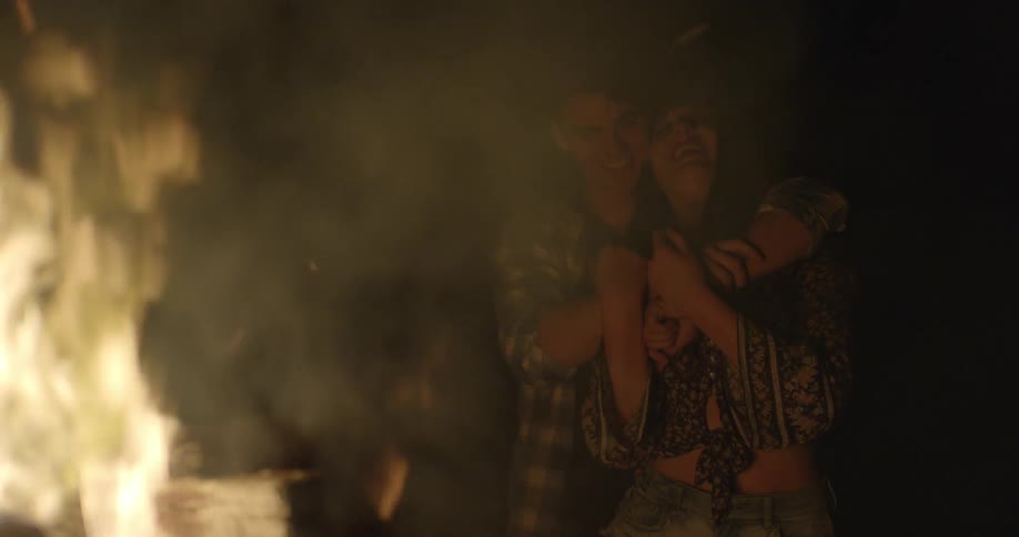 A couple watch the campfire