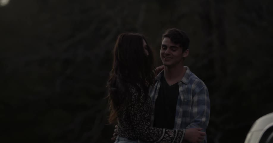 A man and woman smile while dancing outside