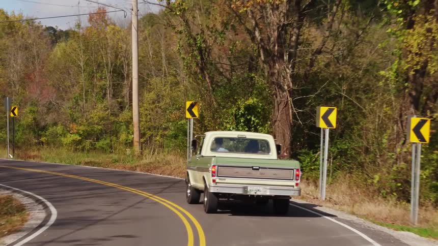An old pickup truck drives in a rural area