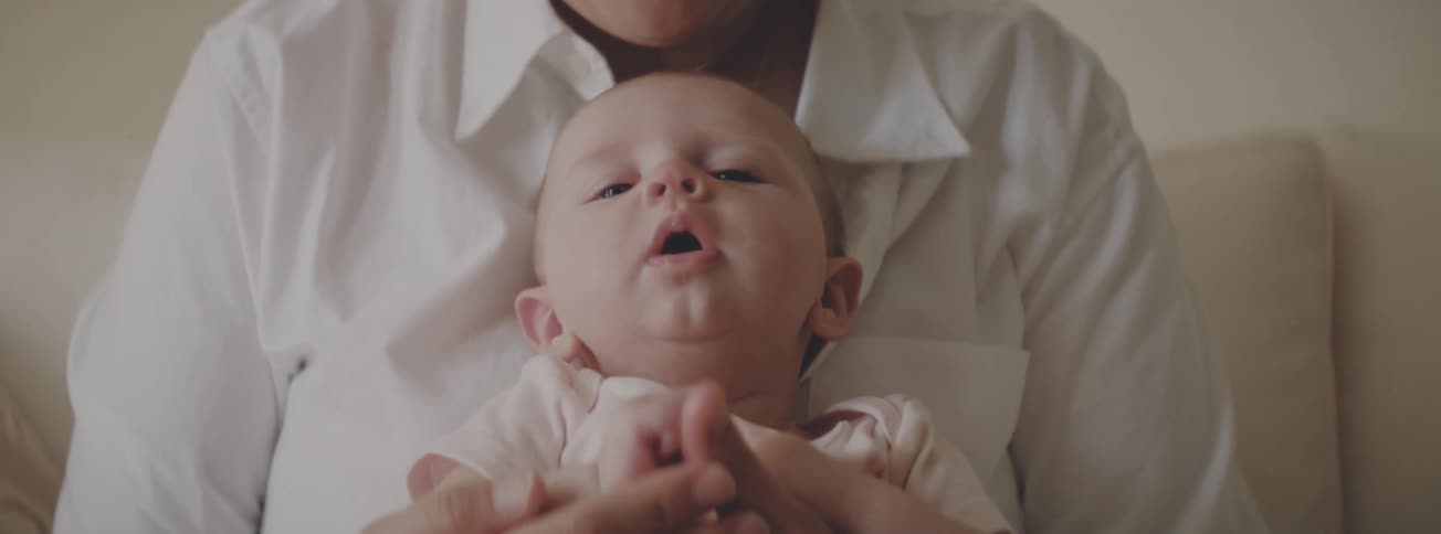 A mother gently holds her newborn baby, kissing its forehead as it peacefully falls asleep in her loving arms
