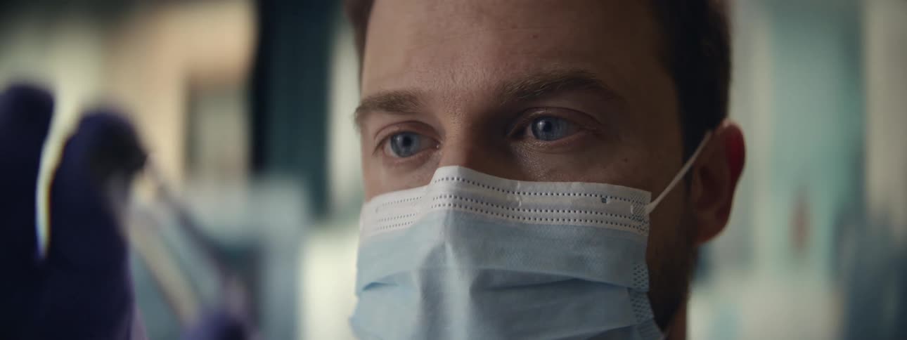 Close-up of a focused male doctor or scientist with blue eyes wearing a protective surgical mask