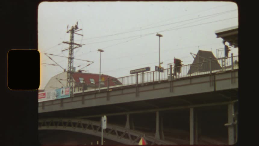 Vintage 8mm film captures a red S-Bahn train passing the Berlin Friedrichstraße station sign