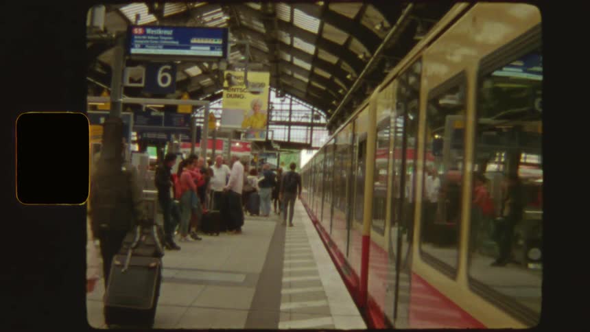 A vintage Super 8mm film captures the moment a train departs from a busy European station platform full of travelers