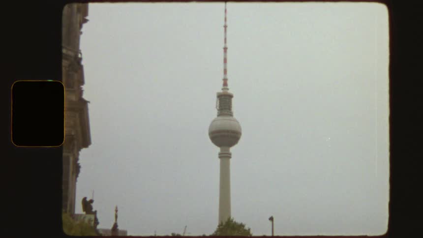 Vintage 8mm film-style shot zooms out from the Berlin TV Tower on an overcast day