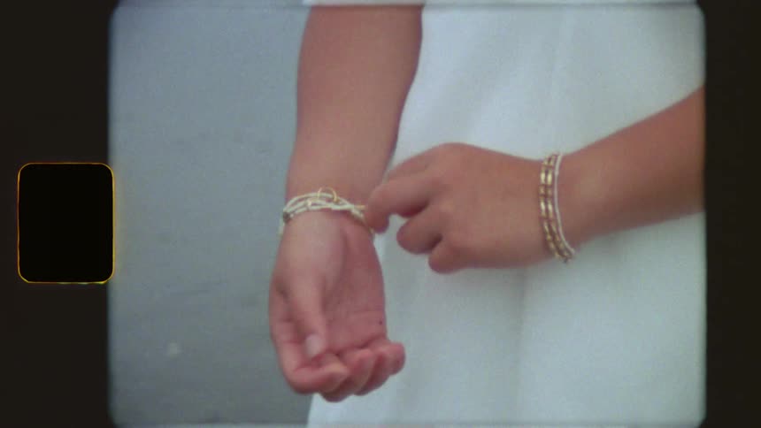 A close-up of a person's hands adjusting beaded bracelets on their wrists, captured with a nostalgic vintage film look