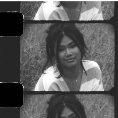 Vintage black and white film strip of a young woman posing thoughtfully in a field of tall grass