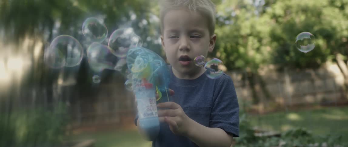 A boy is using a toy gun that shoots bubbles