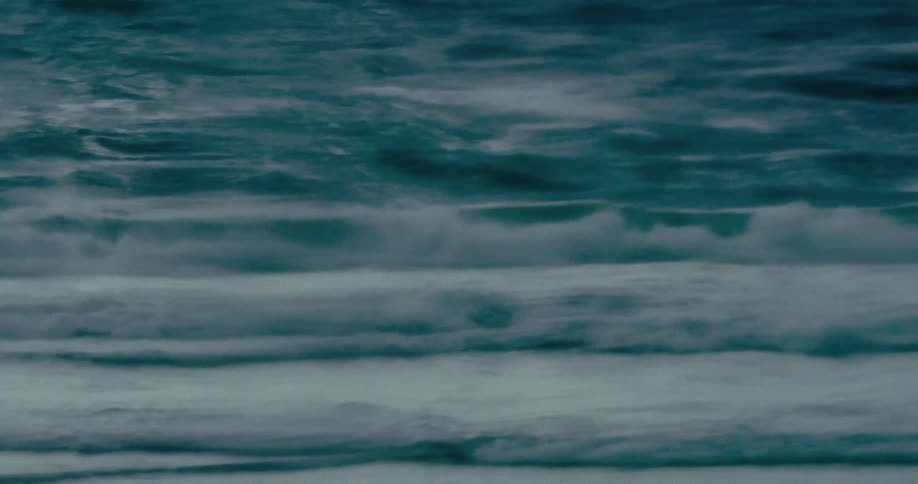 Dark teal ocean waves swell and break in mesmerizing extreme slow motion