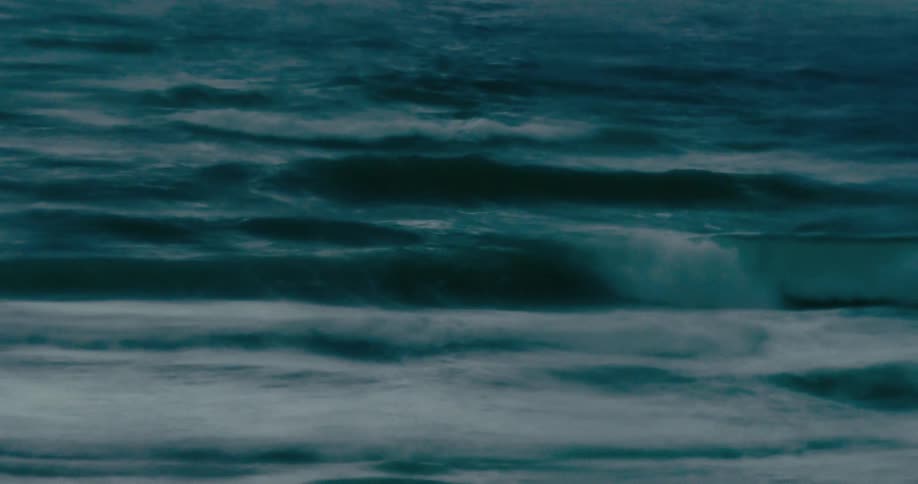 Dark teal ocean waves roll in mesmerizing slow motion creating a moody and abstract background