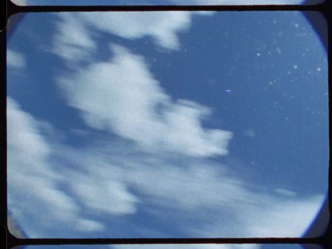 Vintage POV footage speeds along a grassy path before tilting up to a bright, sun-filled sky